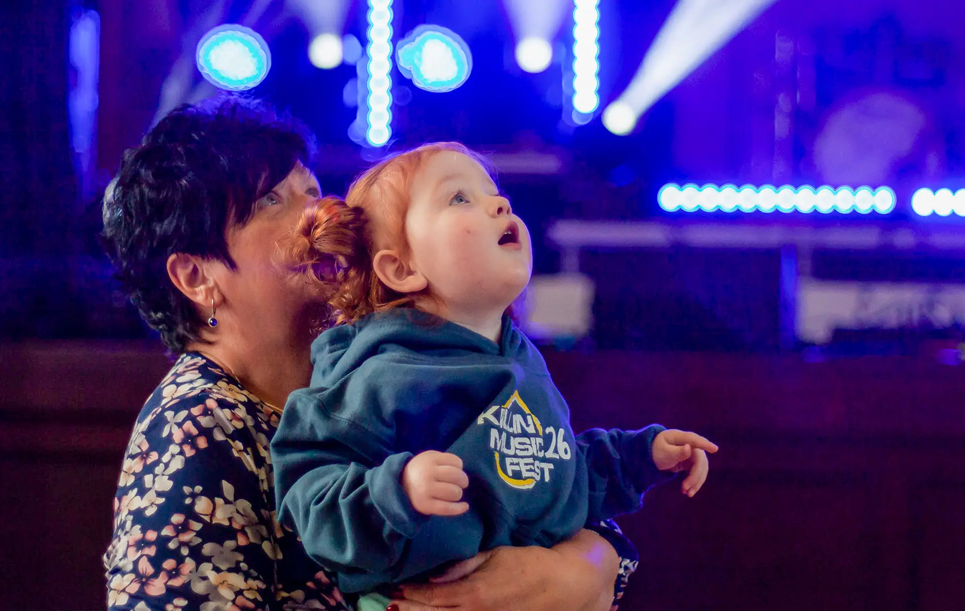 Young child in a Killin Music Fest hoodie watching the stage from the crowd