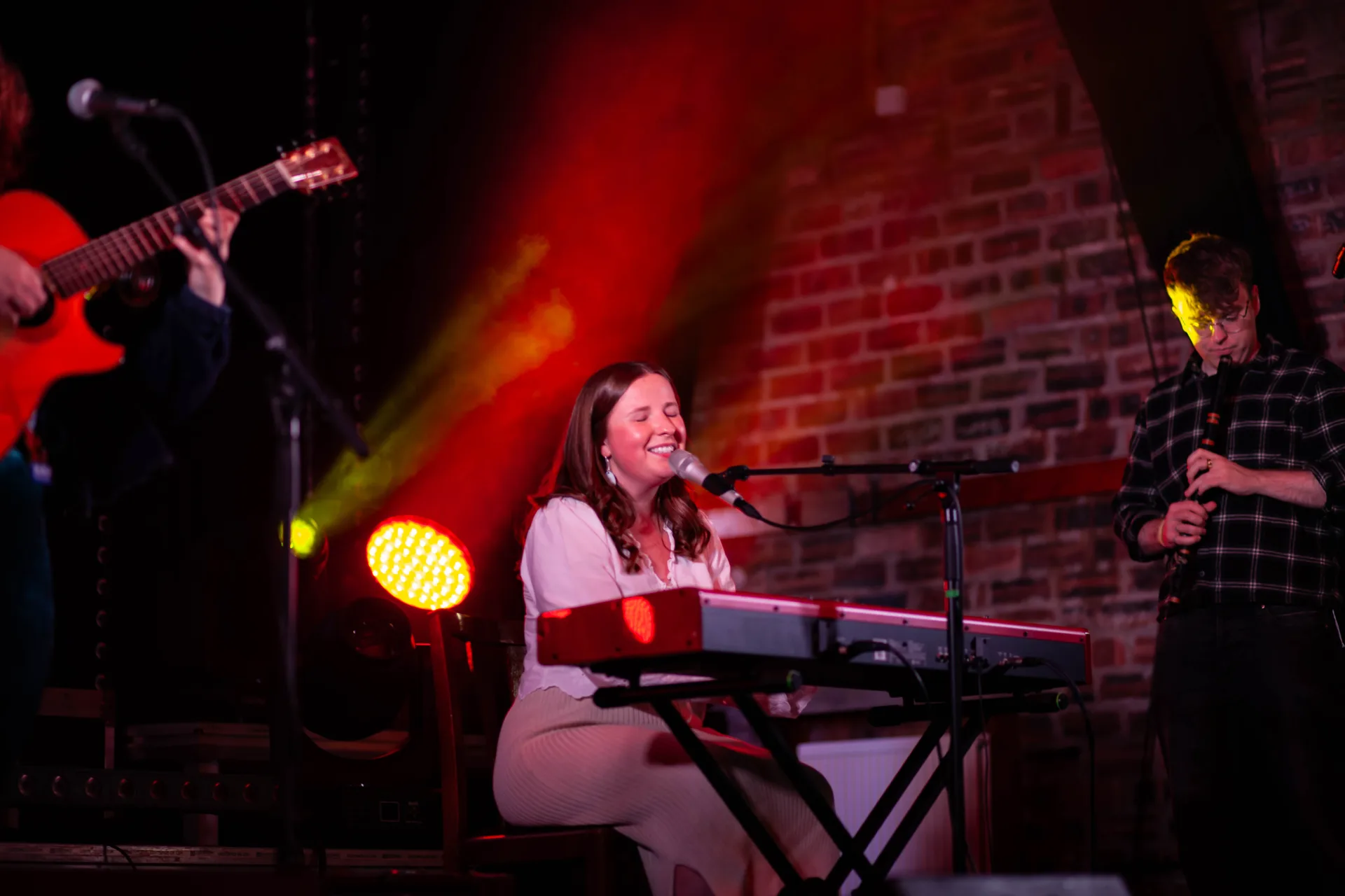 Singer at the keyboard performing under warm red light