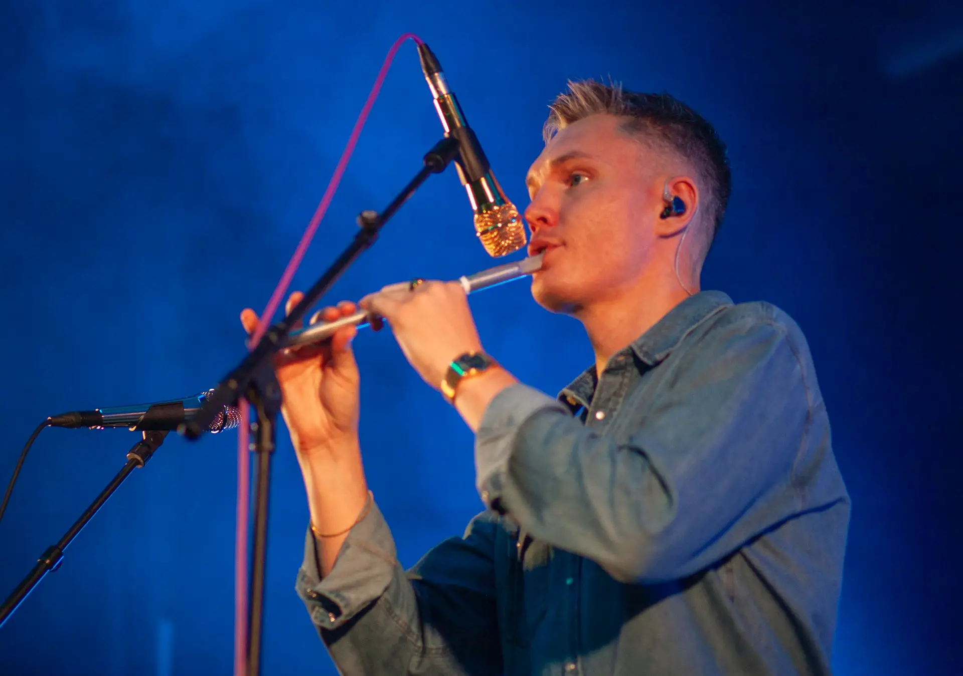 Musician playing the whistle under blue stage lights