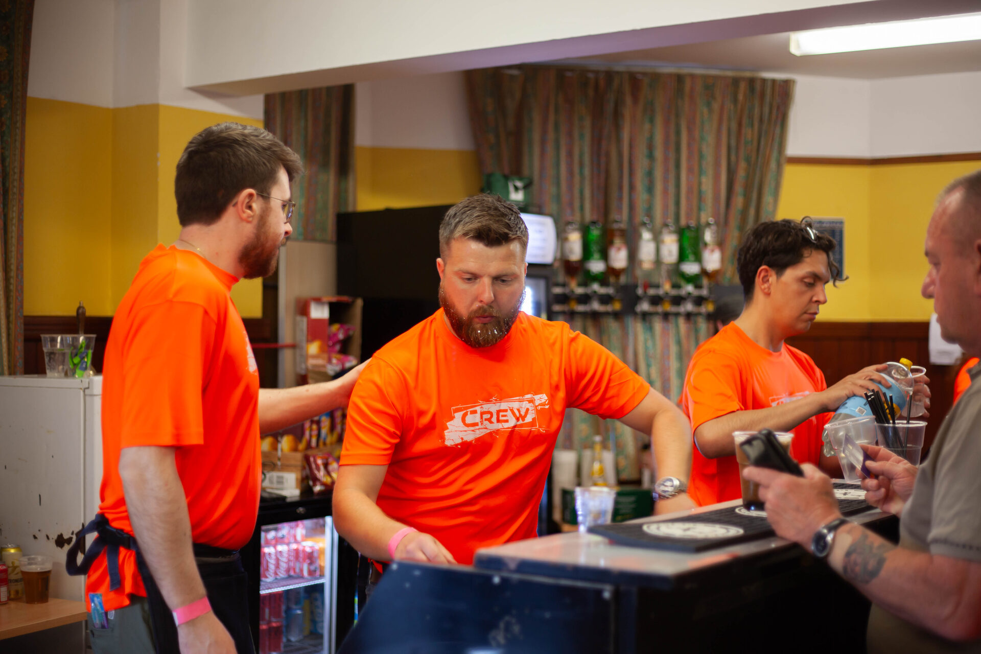 Volunteers in orange crew shirts serving at the bar