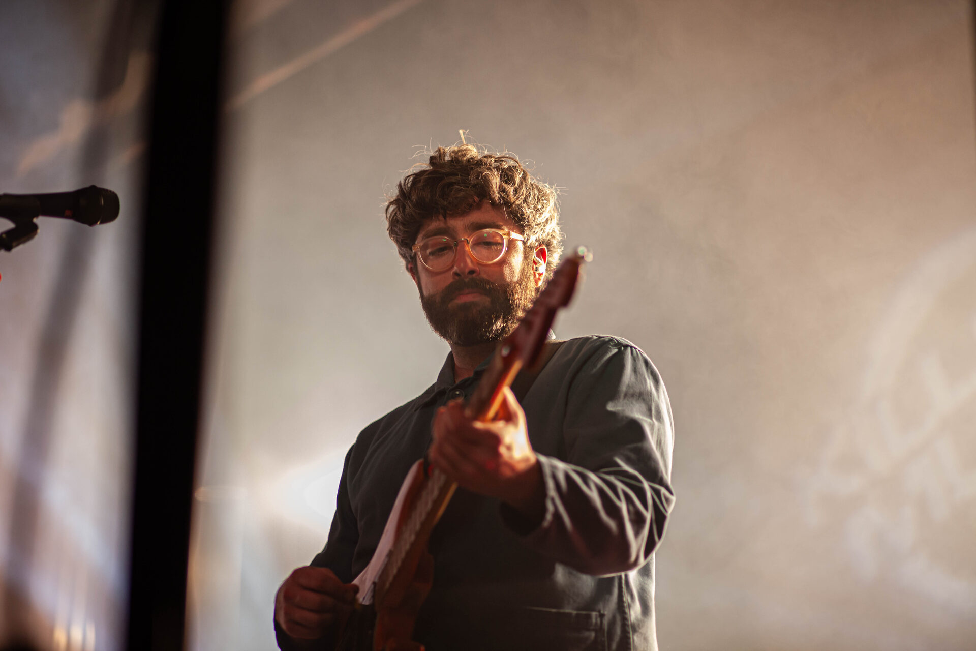 Guitarist performing, lit warm against the stage haze