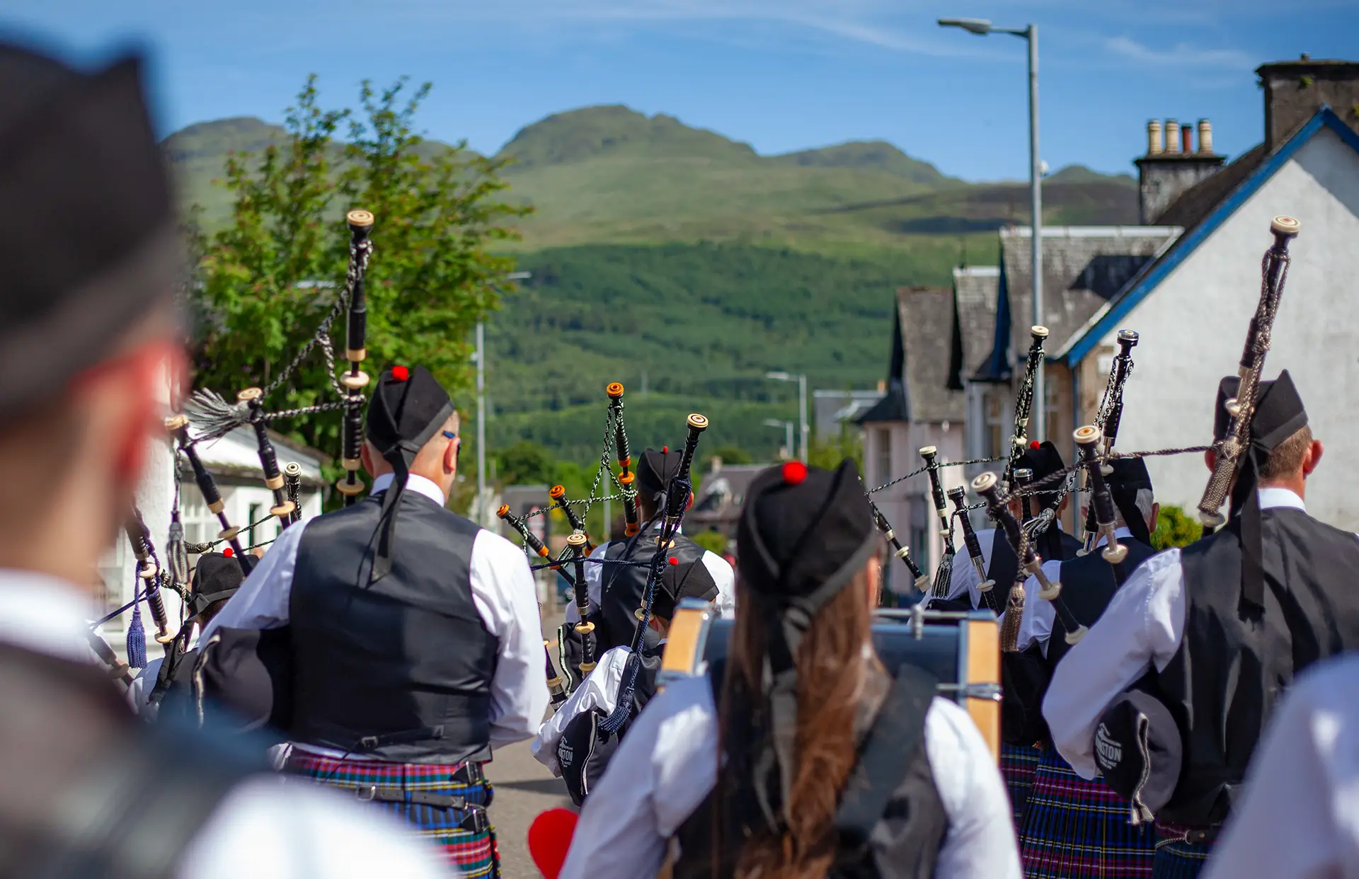 Pipe band marching through Killin with the Highland hills behind