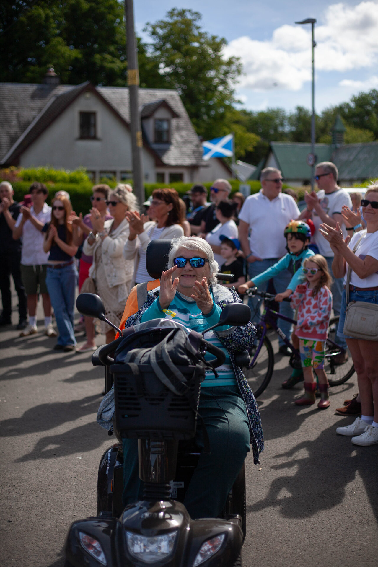 A woman on a mobility scooter clapping among the community day crowd
