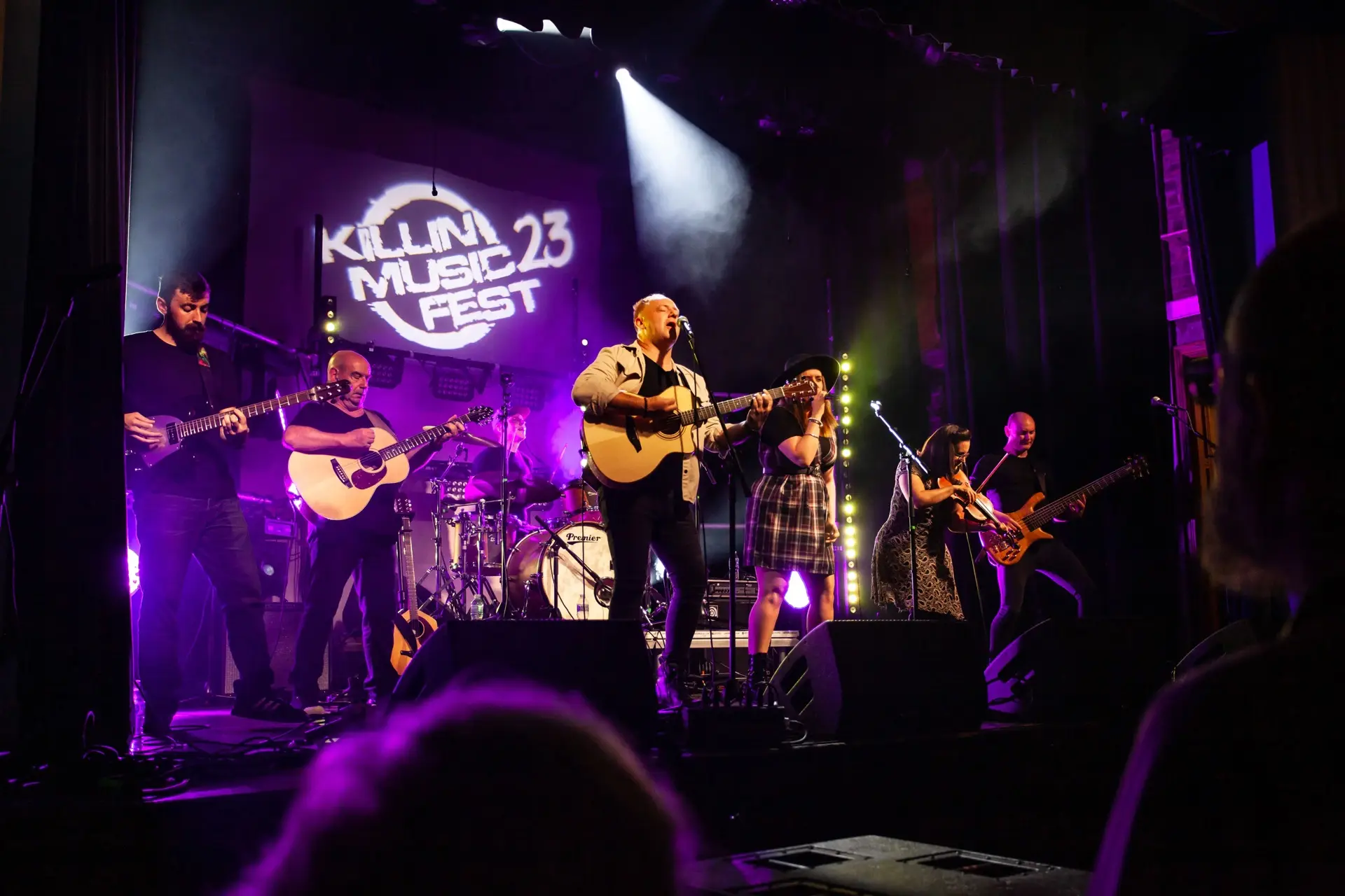 Full band performing under purple lights
